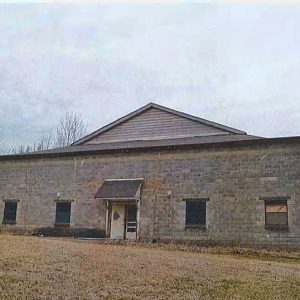 Single-story cement block building with gabled roof and awning over its front doors