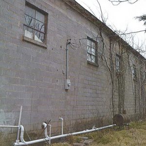 Close-up of cement block building with windows and trees behind it