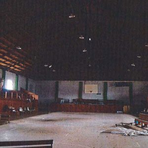 Basketball court with hoop and bleachers inside gymnasium