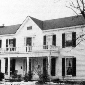 Two-story white house with covered porch and balcony above it