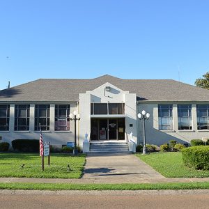 Single-story school building with street lamps in front yard