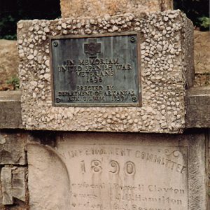 Stone memorial with weathered plaque and engraved base