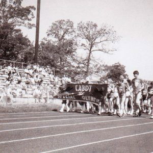 Group of people marching in parade with banner on track