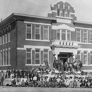 Crowd of students and faculty posing on steps of and in front of multistory building