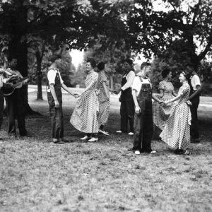 White men and women dancing among trees