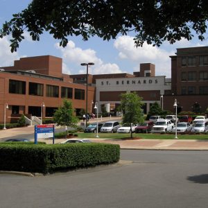 "Saint Bernards" multistory brick hospital complex with driveway parking lot pedestrians and landscaping