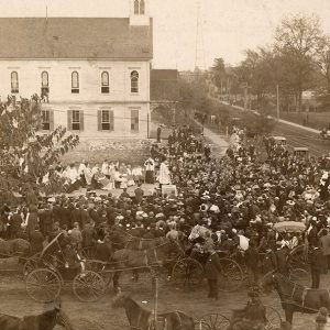 large church congregation gathered outside church building with crowd on street corner