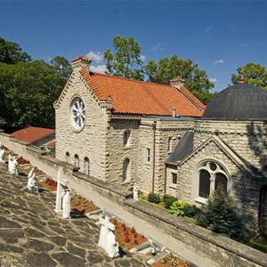 Byzantine church building with round and arched widows and dome with stone wall and cross grave markers