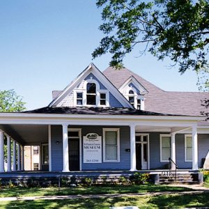 Blue and white multistory house with covered porch and sign