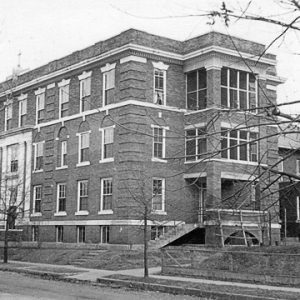 multistory brick building with trees and road