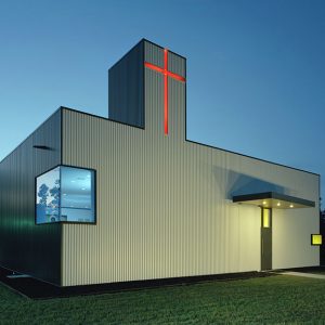 Modern box-shaped church building with red cross and corner windows