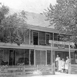 Two-story hotel "Star Hotel" with fence and white staff