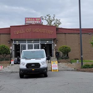 Brick "Hall of Industry" building with glass doors on parking lot