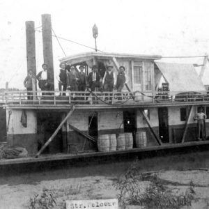 Group of white men stand on upper level of steamboat with group of black men standing on lower level of steamboat in port