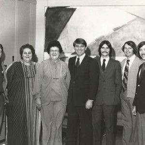 White men in suits standing with white women in dresses