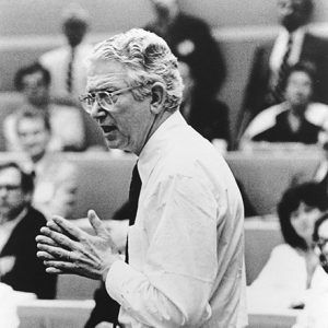 White man with glasses speaking to students