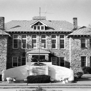 Two-story stone building with stone monument wall and benches