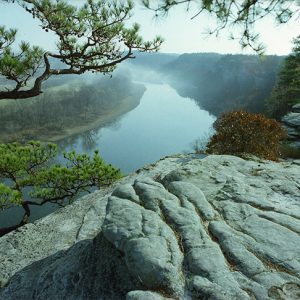 Looking out onto foggy river from rock wall above it