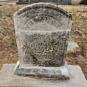 "William C" gravestone in cemetery with other gravestones in the background