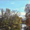 Tree-lined river with fall foliage and blue skies