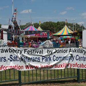 Carnival rides with fence and banner "Strawberry Festival"