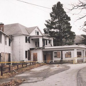 Abandoned run-down hotel building with covered entrance on parking lot