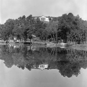 Multistory building and tree covered hill reflected in lake