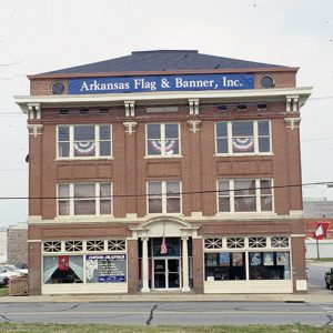 front view of three-story building with a banner reading "Arkansas Flag and Banner, Inc." across the top