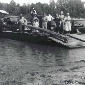 White men women and child with car on ferry boat on river