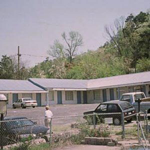 Blue and white motel building with cars in parking lot