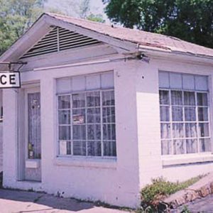 Motel building with window in front and hanging sign saying "office"