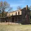 Two-story log house with covered porches on grass