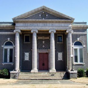 Multistory brick building with covered porch supported by four columns and arched windows with "Temple Beth El" engraved on the front