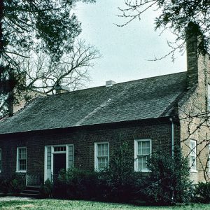 Two-story brick house with framed windows and door on grass