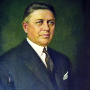 White man in suit with green background