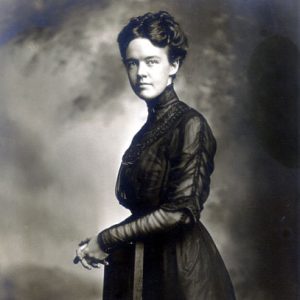 White woman with curly hair posing in fancy dress