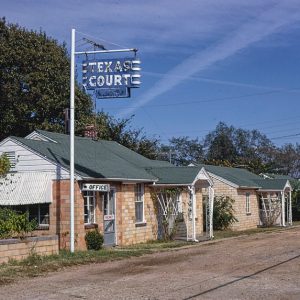 Row of single-story brick buildings with "Texas Court" hanging sign in foreground