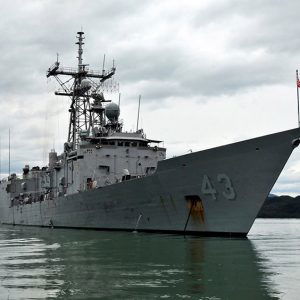 Naval vessel floating in water with land in the distance