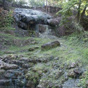 Natural waterfall with rocks and trees on hillside