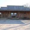 Single-story storefront with covered porch and ice machine on gravel parking lot