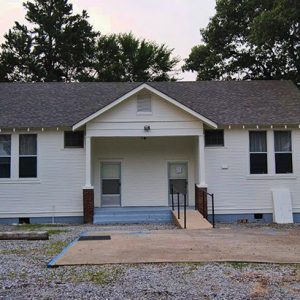 Single-story white building with covered porch and two front doors