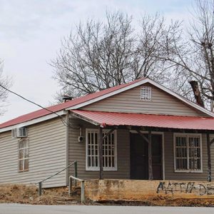 Single-story building with covered concrete porch with black writing on the concrete