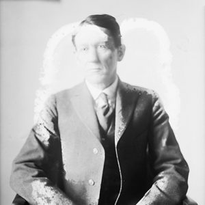 White man in suit sitting in chair