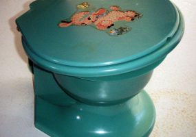 Green toilet with pink lamb and butterfly sticker on its lid