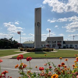 Concrete bell tower outside multistory building with covered porch and circular driveway