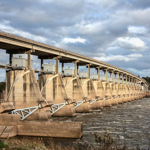 Side view of concrete dam topped by bridge