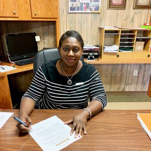 African-American woman in striped shirt sitting at desk in office