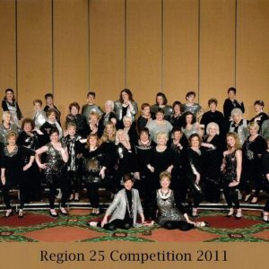 Group of white women in black and sparkly silver dress clothes standing and posing on risers