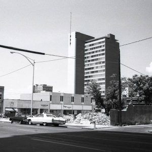 Cars parked on multilane city street with tall multistory building in the background