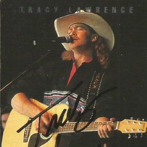 White man in cowboy hat singing and playing an acoustic guitar on concert advertisement